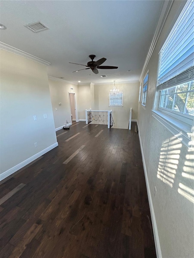 unfurnished living room with ceiling fan with notable chandelier, dark hardwood / wood-style flooring, and ornamental molding