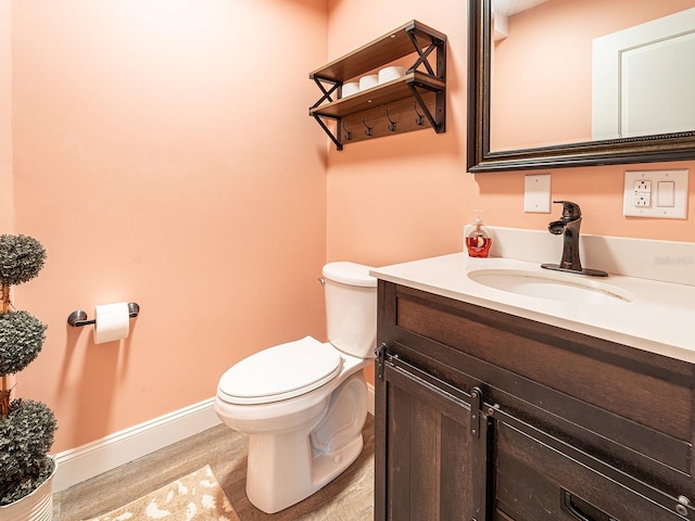 bathroom featuring wood-type flooring, toilet, and vanity