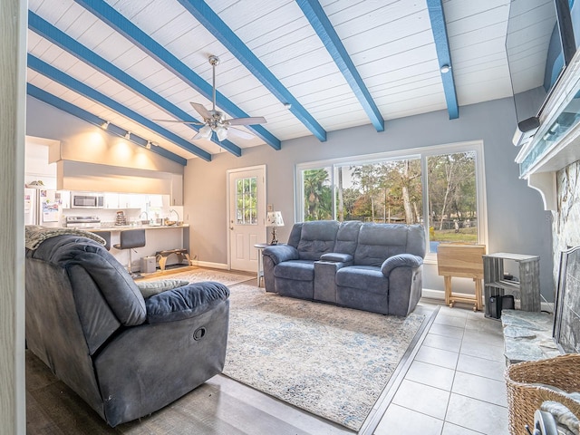 tiled living room with ceiling fan, a fireplace, wooden ceiling, and vaulted ceiling with beams