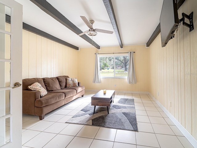 tiled living room featuring ceiling fan, wood walls, and beam ceiling