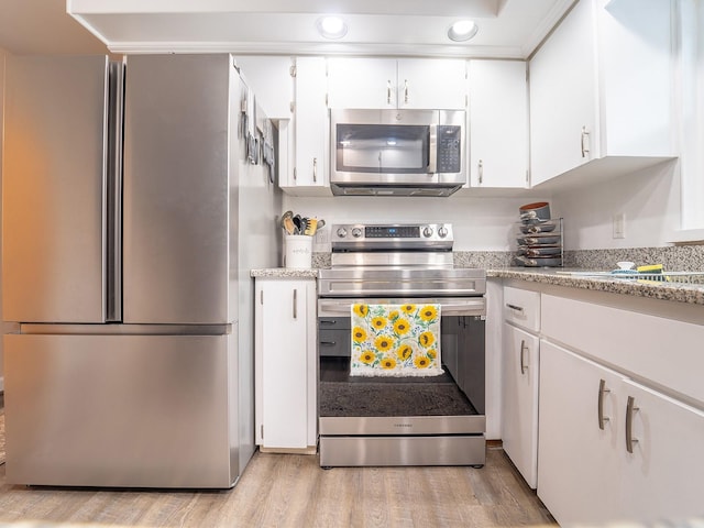 kitchen with light hardwood / wood-style floors, white cabinetry, and stainless steel appliances