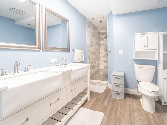 bathroom featuring vanity, hardwood / wood-style flooring, a tile shower, and toilet