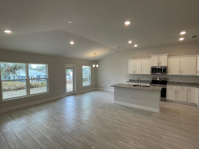 kitchen with lofted ceiling, white cabinetry, stainless steel appliances, stone countertops, and a center island with sink