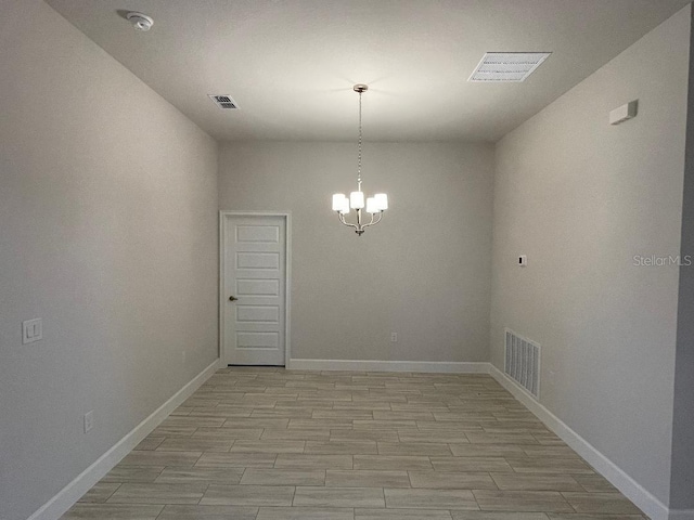 spare room featuring light hardwood / wood-style floors and an inviting chandelier