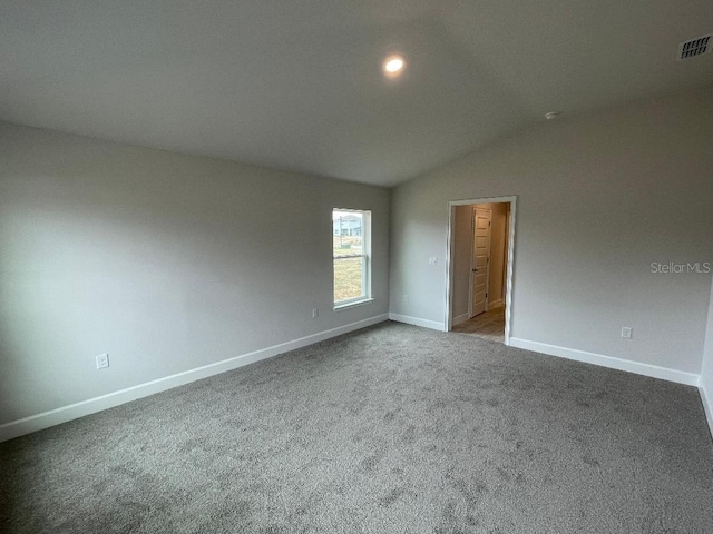 carpeted spare room with lofted ceiling