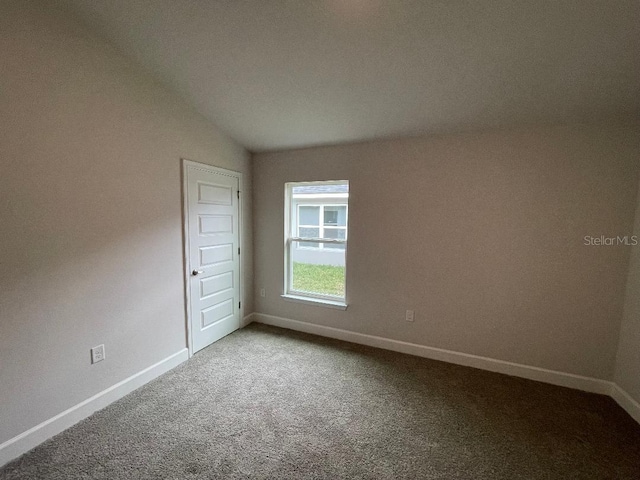 carpeted empty room featuring lofted ceiling