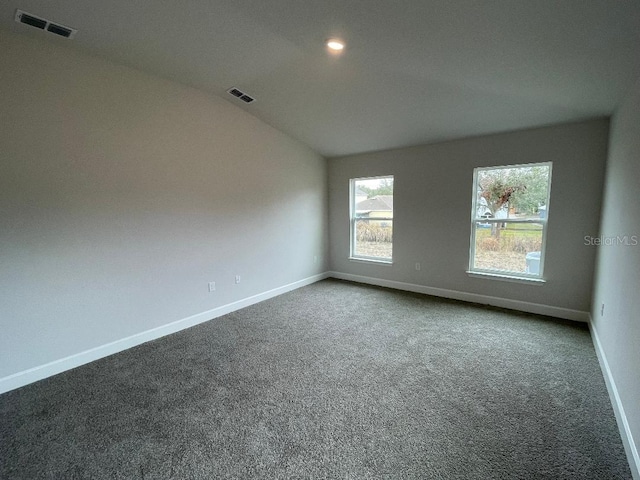 empty room featuring lofted ceiling and dark carpet