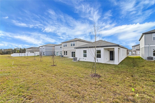 rear view of property with cooling unit and a lawn