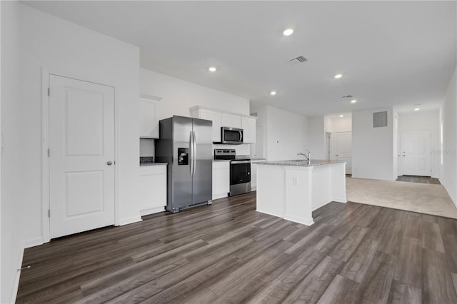 kitchen featuring appliances with stainless steel finishes, dark hardwood / wood-style floors, a kitchen island with sink, white cabinets, and light stone counters