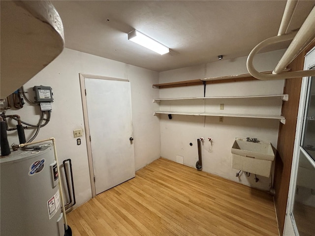 clothes washing area featuring sink, electric water heater, light hardwood / wood-style flooring, and hookup for a washing machine