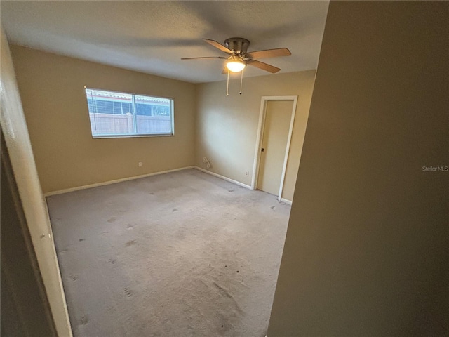 empty room featuring ceiling fan and light carpet