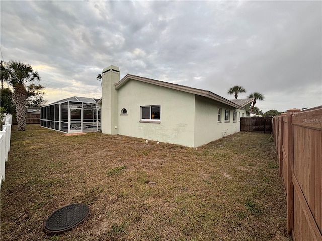 view of side of home with a lanai and a yard