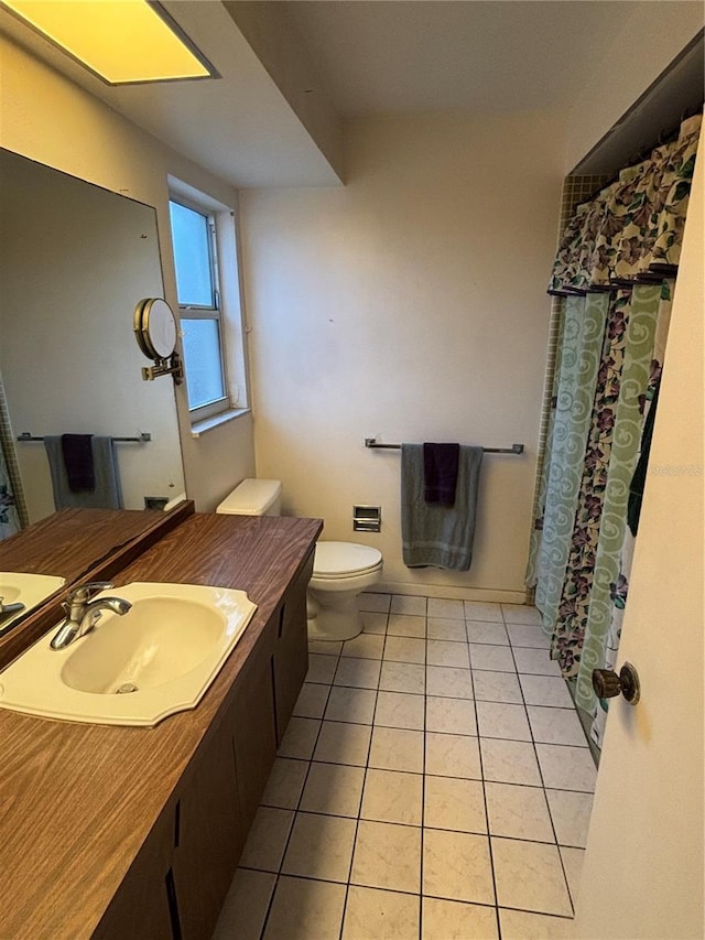 bathroom with toilet, vanity, and tile patterned flooring