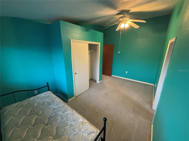 unfurnished bedroom with a textured ceiling, lofted ceiling, a closet, carpet flooring, and ceiling fan