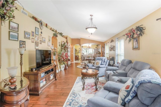 living room featuring lofted ceiling, wood-type flooring, and a notable chandelier