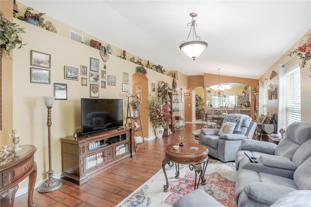 living room featuring vaulted ceiling, a chandelier, and hardwood / wood-style floors