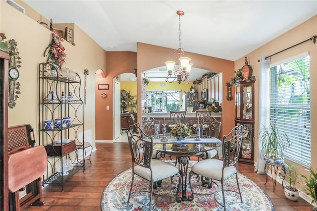 dining area featuring dark wood-type flooring, an inviting chandelier, and lofted ceiling