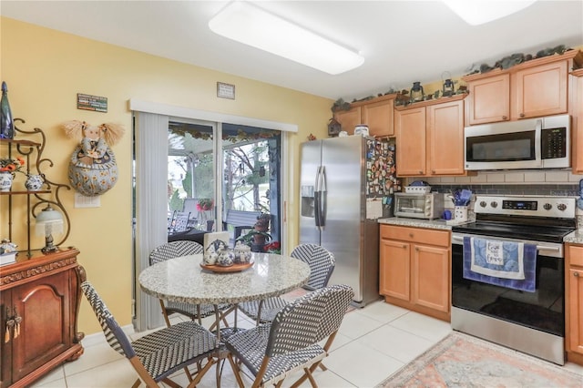 kitchen with tasteful backsplash, appliances with stainless steel finishes, light tile patterned flooring, and light stone counters