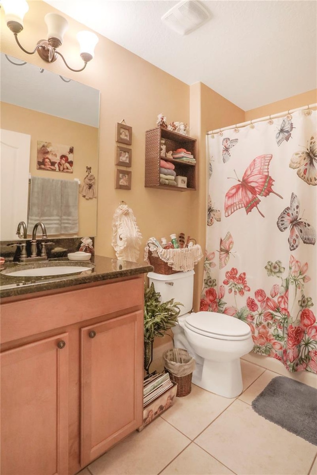 bathroom with toilet, vanity, and tile patterned floors