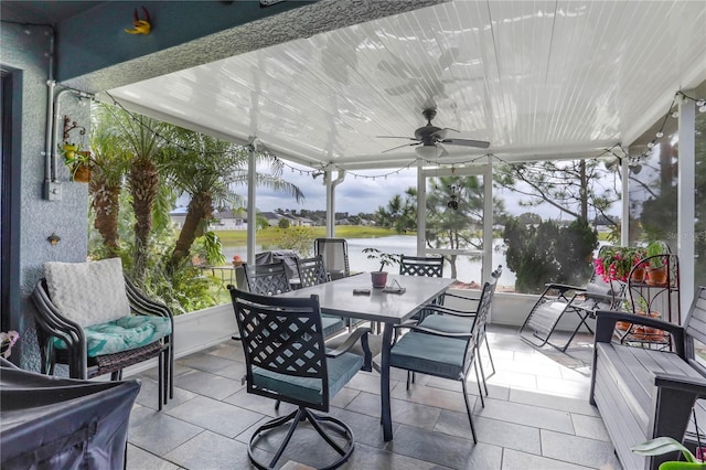 sunroom / solarium with ceiling fan and a water view