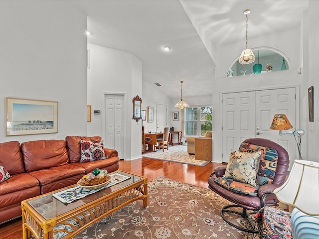 living room with hardwood / wood-style flooring, a chandelier, and high vaulted ceiling