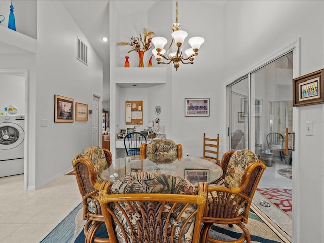 tiled dining room featuring an inviting chandelier, washer / dryer, and high vaulted ceiling