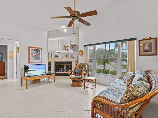 tiled living room featuring a tiled fireplace, a towering ceiling, and ceiling fan