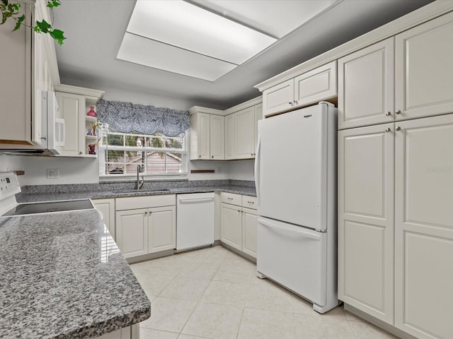 kitchen with sink, white appliances, light tile patterned floors, and white cabinets