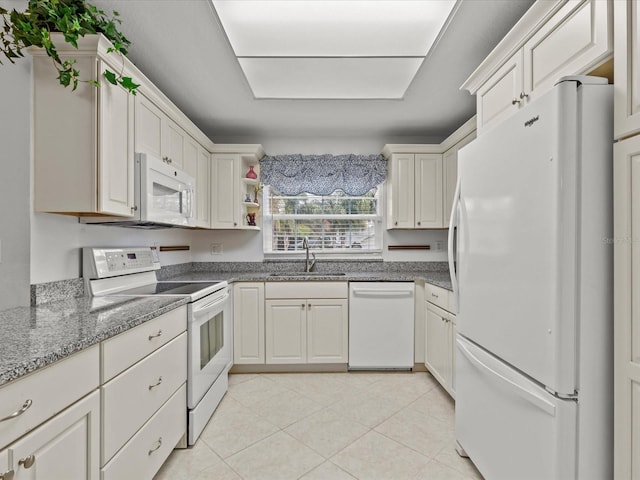 kitchen with light tile patterned flooring, white appliances, light stone countertops, and sink