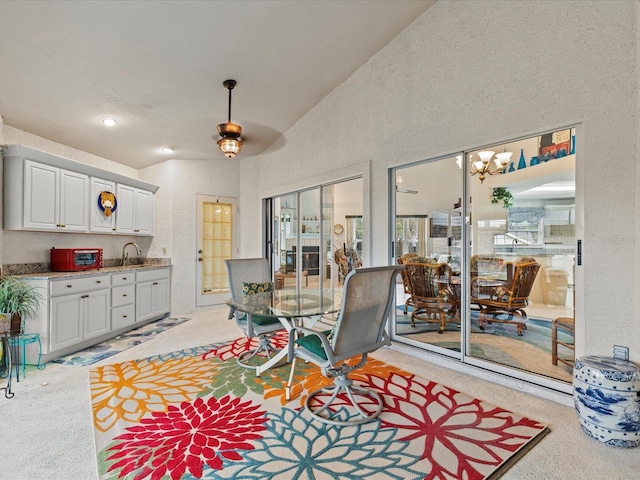 dining area featuring lofted ceiling, sink, and light colored carpet