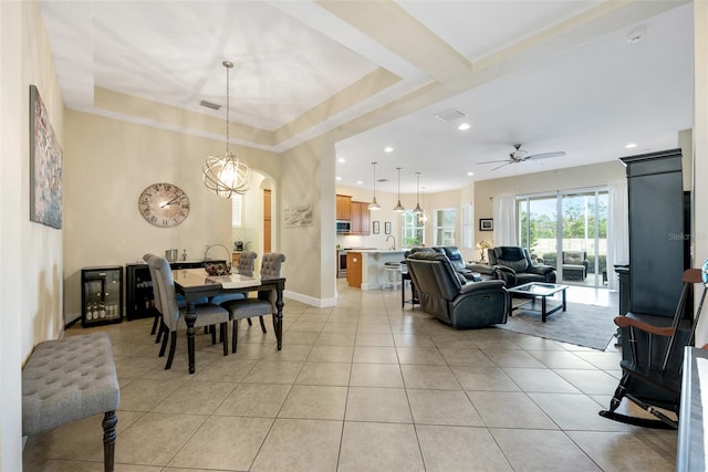 tiled dining area with ceiling fan, sink, and a tray ceiling