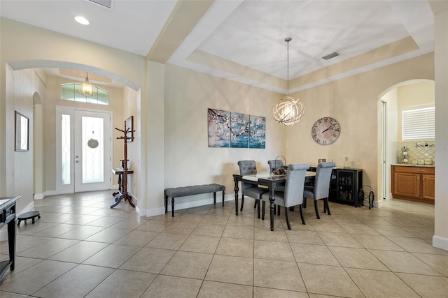 dining area with an inviting chandelier, light tile patterned floors, and a tray ceiling