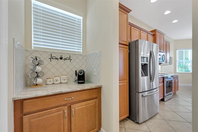 kitchen with light stone counters, light tile patterned floors, stainless steel appliances, and tasteful backsplash