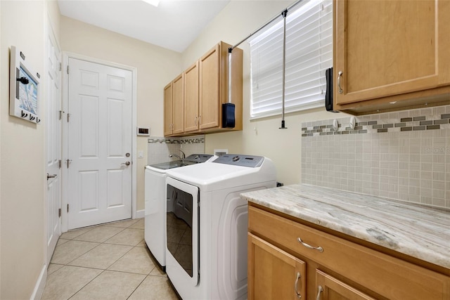 washroom with cabinets, washing machine and dryer, and light tile patterned flooring