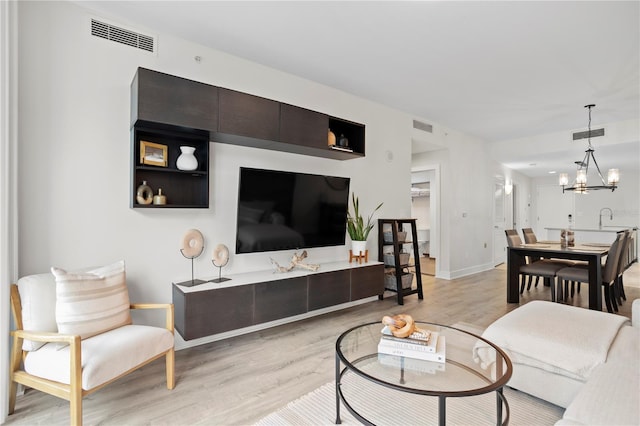 living room featuring light hardwood / wood-style floors, sink, and an inviting chandelier