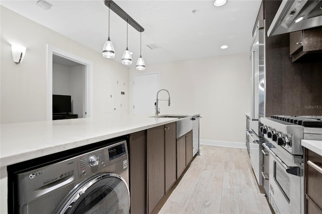 laundry area with washer / clothes dryer, sink, and light hardwood / wood-style flooring