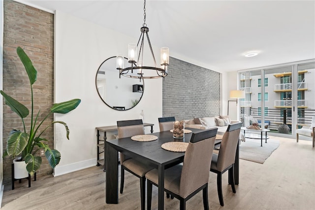 dining area with a wall of windows, light wood-type flooring, and a chandelier