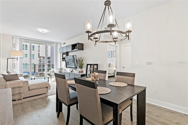 dining area with a chandelier, floor to ceiling windows, and wood-type flooring