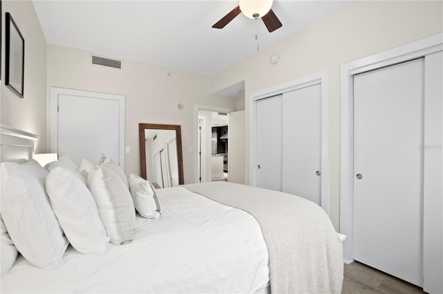 bedroom with ceiling fan, light hardwood / wood-style floors, and multiple closets