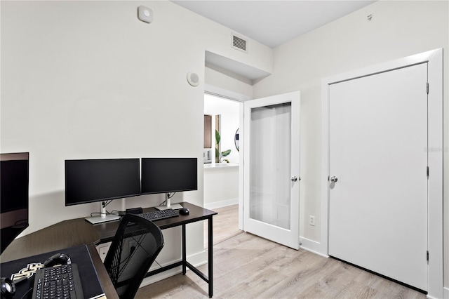 home office with light hardwood / wood-style flooring