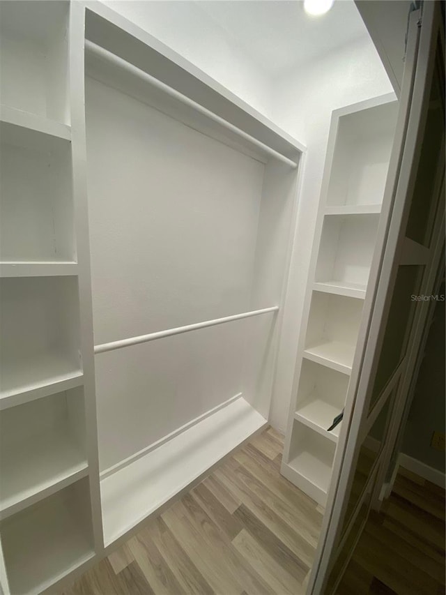 walk in closet with hardwood / wood-style flooring