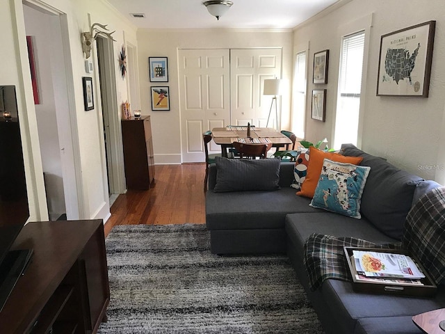 living room with dark wood-type flooring and ornamental molding