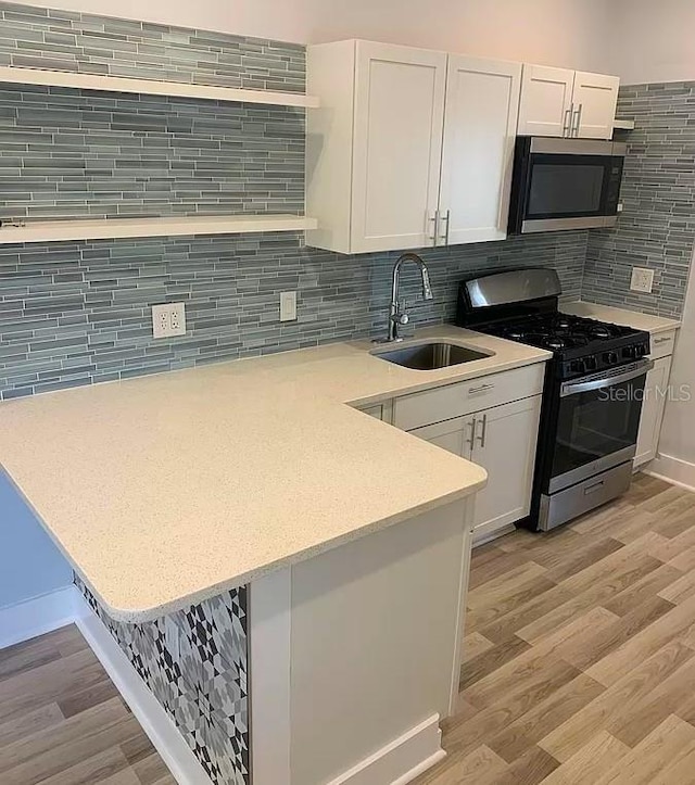 kitchen featuring tasteful backsplash, white cabinets, appliances with stainless steel finishes, and sink