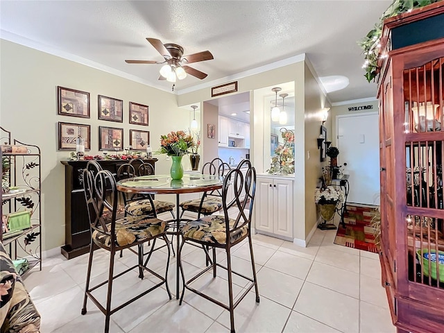 tiled dining room featuring ceiling fan, ornamental molding, and a textured ceiling