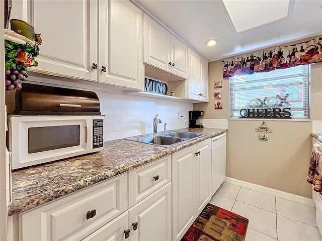 kitchen featuring white appliances, white cabinetry, dark stone counters, sink, and light tile patterned flooring