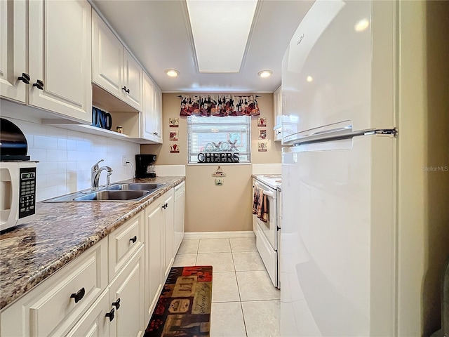 kitchen featuring sink, white cabinets, light tile patterned flooring, white appliances, and stone counters