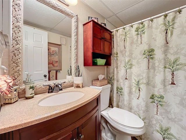 bathroom featuring a drop ceiling, toilet, and vanity