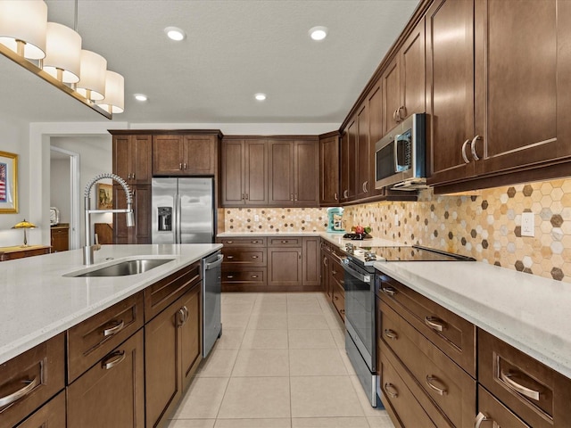 kitchen featuring pendant lighting, sink, stainless steel appliances, light stone counters, and tasteful backsplash