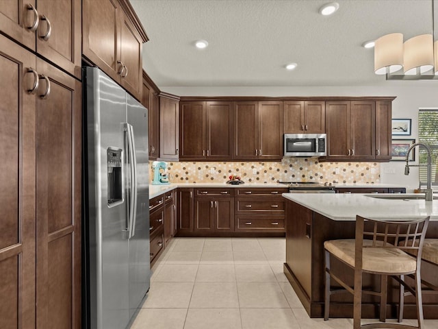 kitchen featuring tasteful backsplash, hanging light fixtures, stainless steel appliances, and sink