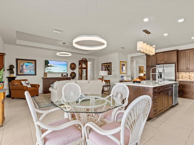 dining space with light tile patterned flooring, sink, and a tray ceiling